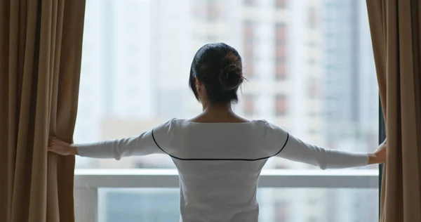 Woman open the curtain at home