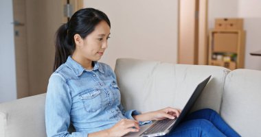 Bilgisayar üzerinde kadın çalışması ve evde kanepede oturmak