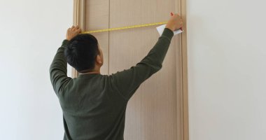 Man measure the door size and write on paper at home clipart