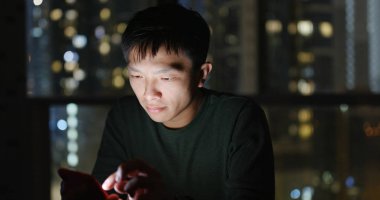 Geceleri cep telefonu kullanan bir adam.