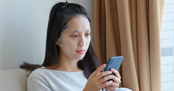 Mujer Aplicar Máscara Facial Uso Del Teléfono Móvil Casa — Foto de Stock