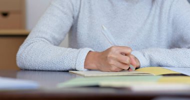 Kadın evdeki deftere yazıyor.