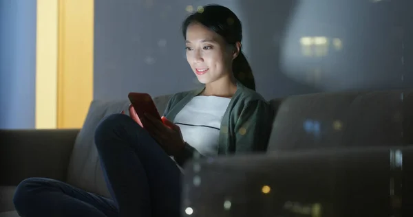 Woman use of mobile phone with window reflection at night