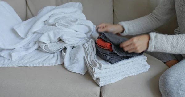 妇女在沙发上折叠干净的软毛巾在家 — 图库照片