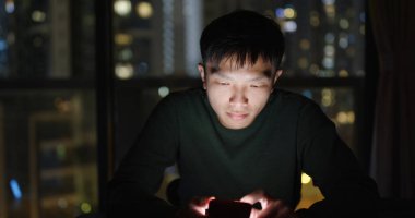 Geceleri cep telefonu kullanan bir adam.