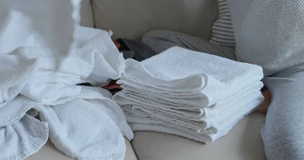 妇女在沙发上折叠干净的软毛巾在家 — 图库照片