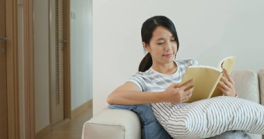 Kadın evde kitap okuyor.