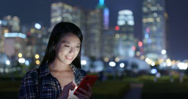 Geceleri Asyalı kadın cep telefonu kullanıyor.