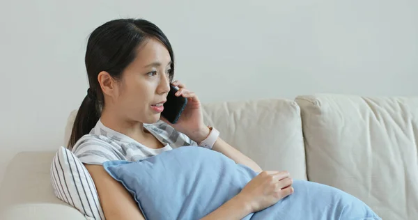 女人用手机说话 坐在家里的沙发上 — 图库照片
