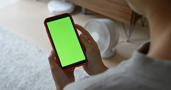 Kobieta trzymać telefon komórkowy z zielonym ekranem w domu — Zdjęcie stockowe
