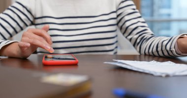 Kadın faturayı evde cep telefonuna kaydediyor.