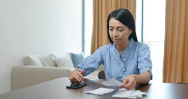 Evde kredi kartı faturası sayan bir kadın