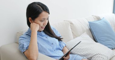 Evdeki tablet bilgisayarda çalışan kadın.