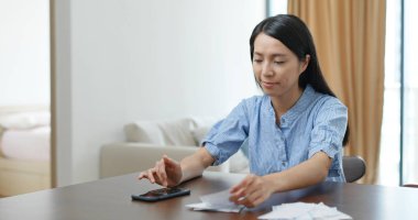 Evde kredi kartı faturası sayan bir kadın