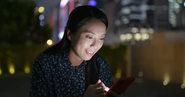 Woman use of cellphone in city at night