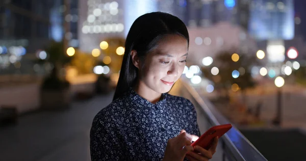 女性は携帯電話で読んで外に座る — ストック写真