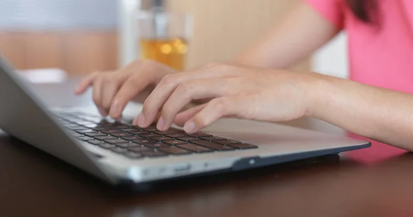 Woman types on laptop computer at home