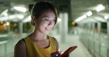 Kadın geceleri şehirdeki akıllı telefonlara bakar.