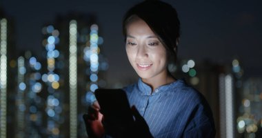 Kadın, gece binanın arka planındaki cep telefonuna bak.