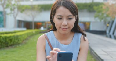 Kadın parktaki cep telefonuna bak.