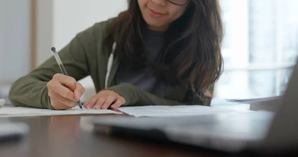 Woman write on the report, study for the exam at home