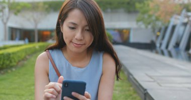 Parkta kadın akıllı telefonu kullanıyor.