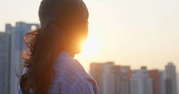 女人看着城市里的建筑 在夕阳西下思考 — 图库照片