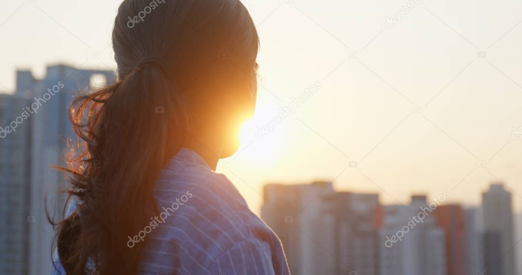 Woman look at the building in city and thinking under sunset