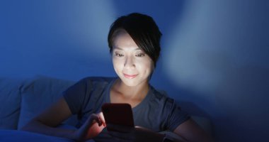 Kadın akşamları evdeki cep telefonuna bakar. 