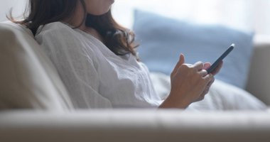 Asyalı kadın evde akıllı telefon kullanıyor.