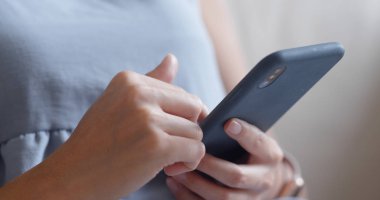 Evde akıllı telefon kullanan bir kadın.