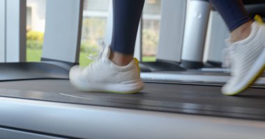 Kadın bacaklar spor salonunda koşu bandı üzerinde koşmak