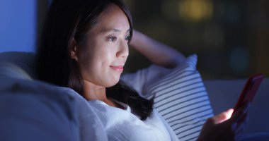 Kadın akşam evde cep telefonu okuyun