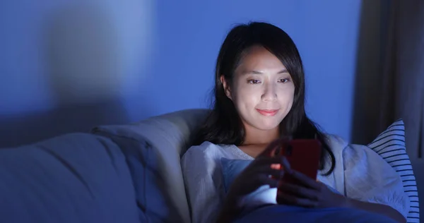 Wanita membaca di ponsel di rumah di malam hari — Stok Foto