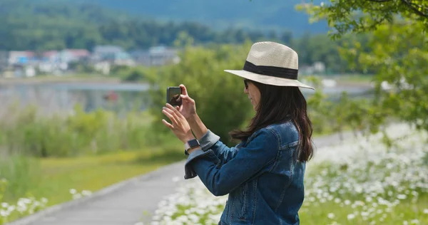 Vrouw neemt foto met mobiele telefoon op het platteland — Stockfoto