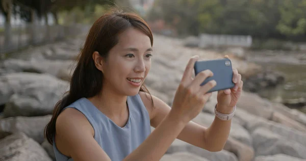 Frau fotografiert mit Handy und sitzt am Meer — Stockfoto