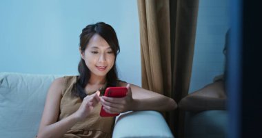 Akşam evde cep telefonu kullanan bir kadın.