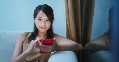 Akşam evde cep telefonu kullanan bir kadın.