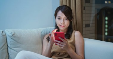 Kadınlar kanepeye oturur ve internet için cep telefonu kullanır.