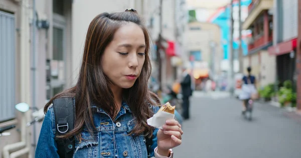 Путешественница ест Тайяки на улице Токио — стоковое фото