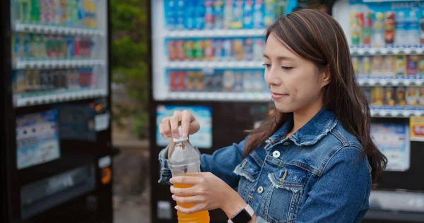 女性は自動販売機でジュースのボトルを飲む — ストック写真