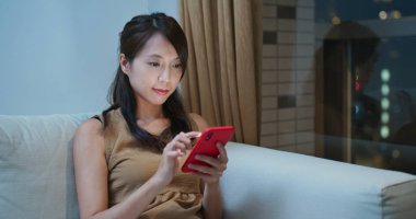 Kadınlar kanepeye oturur ve internet için cep telefonu kullanır.