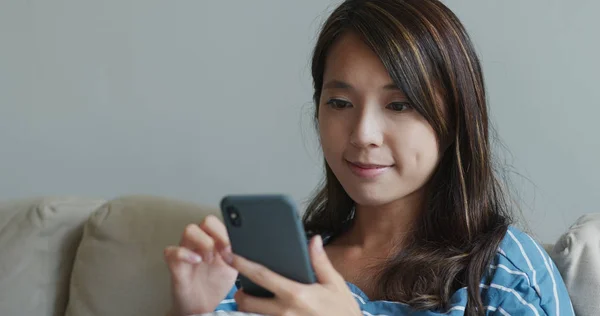 Donna guarda il telefono cellulare a casa — Foto Stock