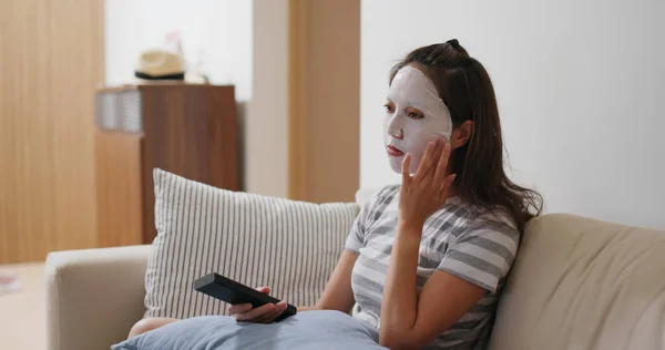 Mulher aplicar máscara de papel no rosto e assistir tv em casa — Fotografia de Stock