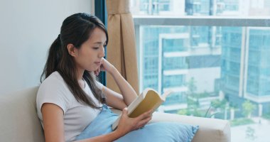 Evde kitap okuyan bir kadın.