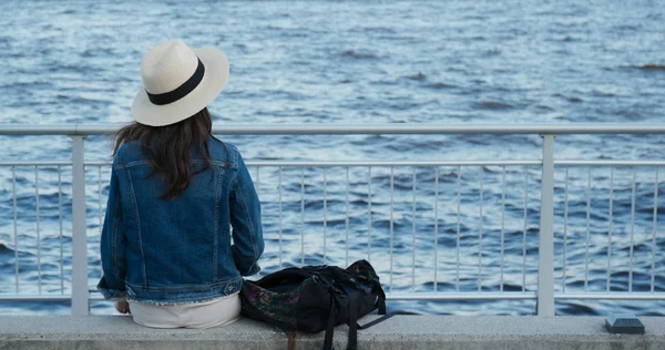 Γυναίκα κάθεται στην πλευρά της θάλασσας και να κοιτάξουμε γύρω από το λιμάνι — Φωτογραφία Αρχείου