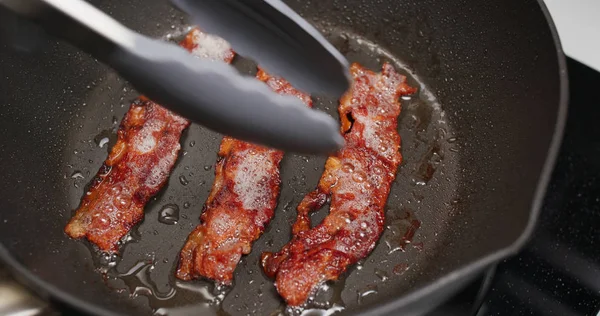 Kahvaltıda kızartma tavasında domuz pastırması pişiriyorum.