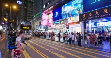 Tsim Sha Tsui, Hong Kong - 06 Temmuz 2019: İnsanlar geceleri caddeden karşıya geçiyor