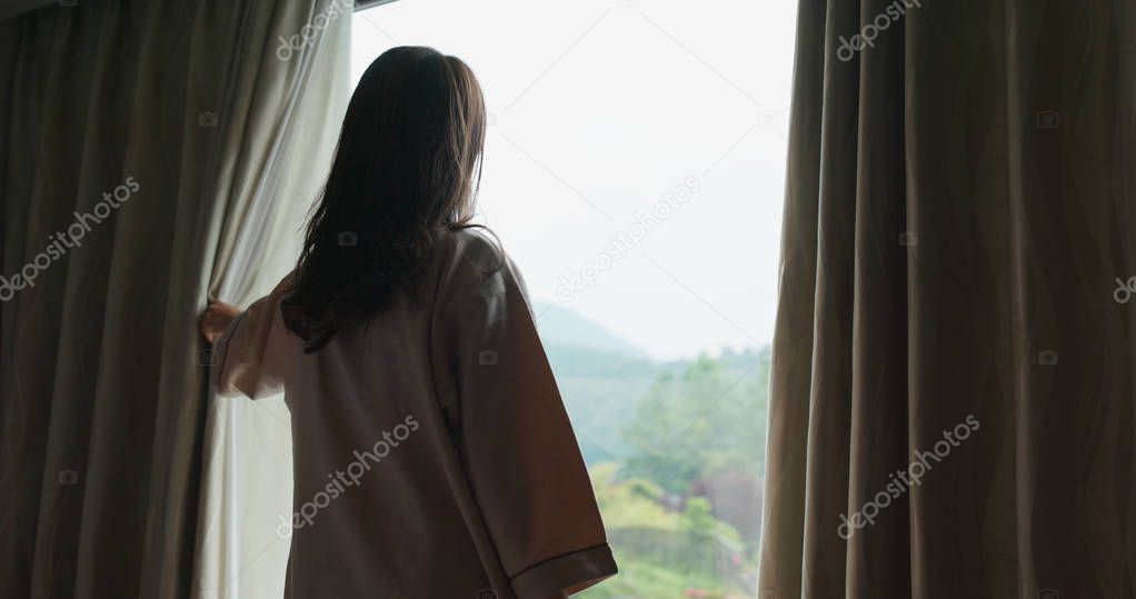 Woman wake up at morning and open the curtain at hotel room