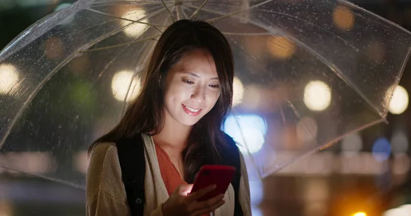 Şehirde şemsiyeli ve cep telefonu kullanan bir kadın — Stok fotoğraf